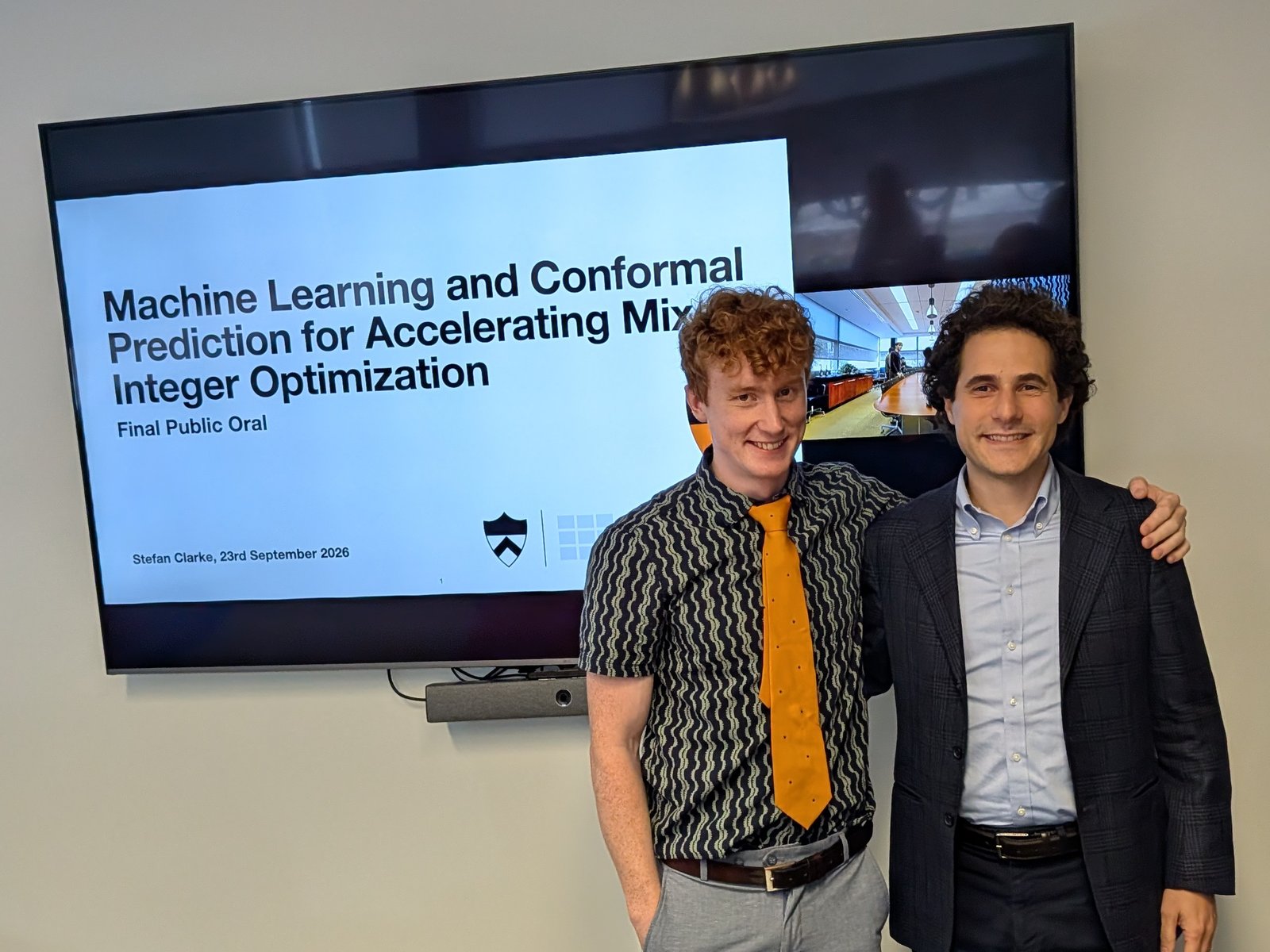 Stefan Clarke and Bartolomeo Stellato in front of the title slide of Stefan's PhD defense